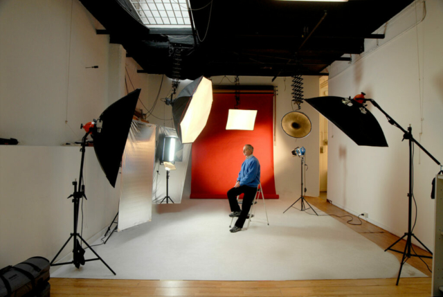 A model was being photographed in Studio C at Instudio.org. The photographer was using a combination of flash and natural light to create a dramatic effect. The model was standing against a red background, which helped to highlight his features. The large space of Studio C gave the photographer plenty of room to work.